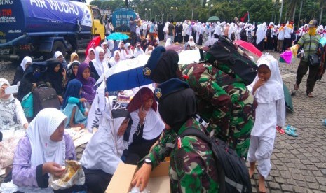 Tentara wanita berjilbab membagikan air mineral di aksi bela islam III di kawasan Monas, Jakarta, Jumat (2/12).