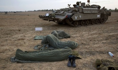  Tentara Zionis Israel tidur dalam kantong di samping tank dekat perbatasan dengan Jalur Gaza, Sabtu (17/11). (Reuters/Ronen Zvulun)