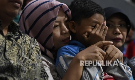 Terpidana kasus pelanggaran Undang-Undang Transaksi dan Informasi Elektronik (UU ITE), Baiq Nuril Maknun (tengah) memeluk anaknya disela-sela pembacaan pertimbangan amnesti untuk dirinya pada rapat paripurna DPR di Kompleks Parlemen Senayan, Jakarta, Kamis (25/7/2019).