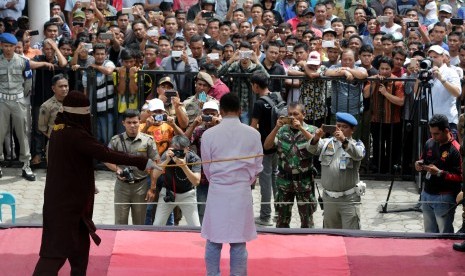 Terpidana (tengah) menjalani hukum cambuk di halaman Masjid Desa Lambaro Skep, Banda Aceh, Aceh, Selasa (18/4). 