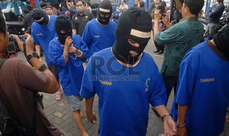 Tersangka didampingi petugas usai memusnahkan barang bukti pada rilis peredaran gelap narkoba di halaman gedung BNN, Jakarta Timur, Selasa (18/2)