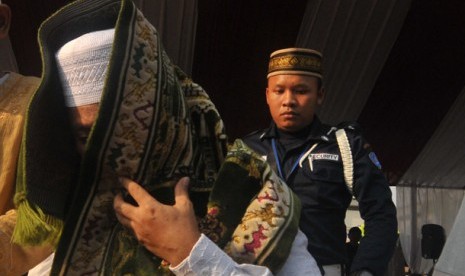 Tersangka penerima suap Hak Guna Usaha kelapa sawit Bupati Buol Amran Batalipu menutup mukanya dengan sejadah menuju mobil tahanan usai mengikuti shalat ied bersama tahanan lainnya di LP Cipinang, Jakarta Timur, Ahad (19/8)