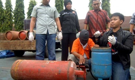 Tersangka pengoplos elpiji ilegal (kedua kiri) mempraktikan cara pengoplosan ketika ungkap kasus di Mapolres Pelabuhan Tanjung Perak Surabaya, Jatim, Jumat (10/1). 