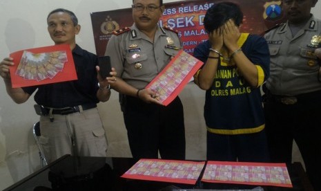 Tersangka Revangga dan barang bukti lembaran-lembaran uang palsu saat berada di Polsek Dau Kabupaten Malang, Selasa (24/1).