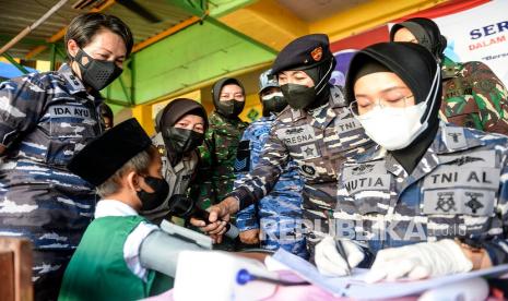 Tertua Korps Wanita TNI AL (Kowal) Wilayah Jakarta Laksamana Pertama TNI Tresna Kusumawati (kedua kanan) bertanya kepada murid sekolah dasar (SD) sebelum mendapatkan vaksin COVID-19 saat serbuan vaksin di Madrasah Ibtidaiyah Al-Wathoniyah di Rorotan, Jakarta, Senin (3/1/2022). Kegiatan vaksinasi tersebut digelar dalam rangka menyambut HUT ke-59 Kowal yang dirayakan setiap 5 Januari sekaligus mendukung program pemerintah terkait pembelajaran tatap muka (PTM). 