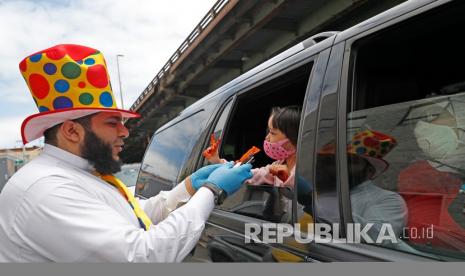   Relawan dari Muslim Community Center Iman Mohamed memberikan permen ke seorang anak saat perayaan Hari Raya Idul Fitri di New York, Ahad (24/5) waktu setempat.