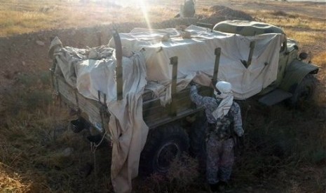 This image posted by the Raqqa Media Center, a Syrian opposition group, shows a fighter from the Islamic State group inspecting a military truck in Raqqa, Syria, Thursday, Aug. 7, 2014. 