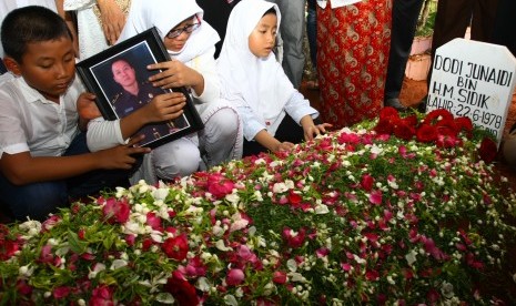 Tiga anak almarhum Dodi Junaidi (40), Zia (kiri), Mutia (tengah) dan Putri (kanan) berdoa di pusara ayahnya seusai dimakamkan di Rempoa, Tangerang Selatan, Banten, Senin (5/11/2018).