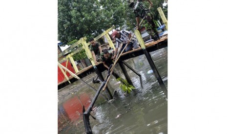 Tiga anggota Armed TNI AD bersama warga berusaha mengangkat ranting kayu dan sampah dari kanal di Kecamatan Maccini Sombala, Makassar, Sulawesi Selatan, Minggu (22/3). 