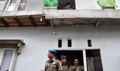 Tiga anggota Satuan Polisi Pamong Praja (Satpol PP) berdiri di depan pintu rumah kos usai gelar razia.