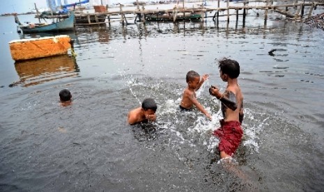 Tiga orang anak kecil mandi di kawasan kumuh di kawasan Muara Angke Jakarta, Selasa (2/12).