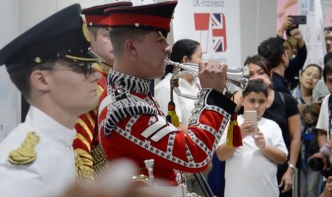 Tiga orang angota militer Kerajaan Inggris yang berseragam lengkap memberikan sajian musik marching band di Statiun MRT Dukuh Atas, Jakarta.