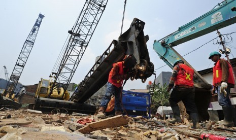 Tiga pekerja menyiapkan tiang pancang yang digunakan untuk pemasangan turap bantaran Sungai Ciliwung di Kampung Pulo, Jakarta, Selasa (25/8). 