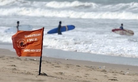 Tiga wisatawan nekat berselancar meski telah dipasangi bendera merah sebagai tanda larangan berenang karena berbahaya di Pantai Kuta, Bali.  (Foto Ilustrasi)