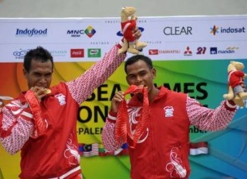 Tim dayung Indonesia,Anwar Tarra (kiri) dan Eka Octarorianus (kanan) mengigit medali emas usai penyerahan medali pada nomor final Kano 200 meter C2 putra SEA Games XXVI di arena dayung Situ Cipule, Karawang, Jawa Barat, Minggu (13/11).