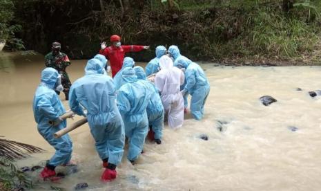 Tim MDMC Kulon Progo harus melalui jalan yang terjal dan mengarungi sungai untuk tiba di permakaman yang disediakan keluarga pasien positif Covid-19.