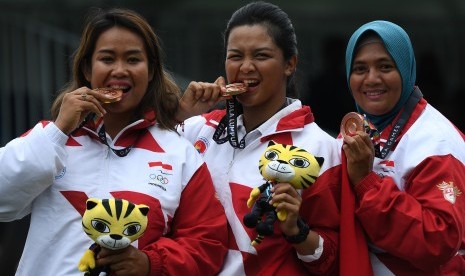 Tim panahan putri Indonesia Rona Siska Sari (kiri), Dellie Threesyadinda (tengah) dan Triya Resky Adriyani menggigit medali perunggu usai penyerahan medali nomor compound beregu putri SEA Games XXIX di Synthetic Turf Fild, kawasan Stadion Bukit Jalil, Kuala Lumpur, Malaysia, Kamis (17/8).