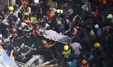 Tim penyelamat membawa mayat seorang korban di lokasi sebuah bangunan yang runtuh di Mumbai, India, Selasa, 16 Juli 2019.