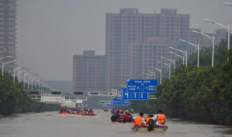 Tim penyelamat menggunakan perahu karet mengevakuasi warga yang terjebak melalui banjir di Zhuozhou di provinsi Hebei, China utara.