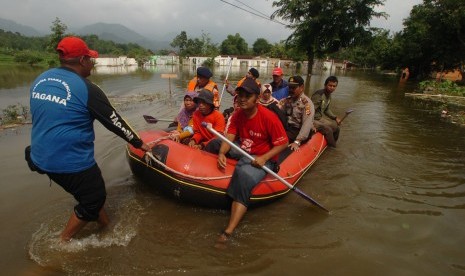 Tim SAR gabungan membantu warga menyebrangi jalan yang digenangi air Waduk Jatigede di Darmaraja, Sumedang, Jawa Barat, Senin (16/2). 