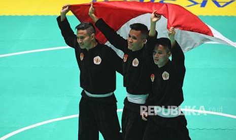 Tim silat Indonesia peraih medali emas Nunu Nugraha (tengah), Asep Yuldan Sani (kiri) dan Anggi Faisal Mubarok (kanan) merayakan kemenangan dengan membentangkan bendera merah putih usai meraih medali emas dalam final beregu putra pencak silat seni Asian Games 2018 di Padepokan Pencak Silat Taman Mini Indonesia Indah (TMII), Jakarta, Senin (27/8). 