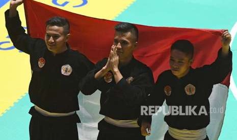 Tim silat Indonesia peraih medali emas Nunu Nugraha (tengah), Asep Yuldan Sani (kiri) dan Anggi Faisal Mubarok (kanan) merayakan kemenangan dengan membentangkan bendera merah putih usai meraih medali emas dalam final beregu putra pencak silat seni Asian Games 2018 di Padepokan Pencak Silat Taman Mini Indonesia Indah (TMII), Jakarta, Senin (27/8). 