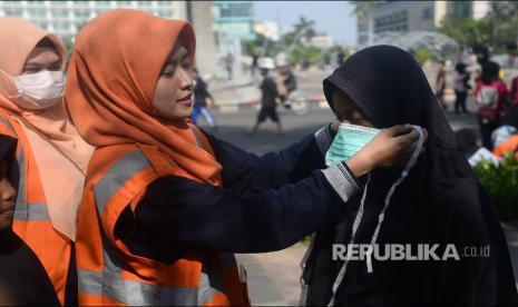 Tim Tanggap Covid-19 Suku Dinas Kesehatan Jakarta Pusat mencontohkan cara memakai masker yang benar saat sosialisasi Covid-19 di Area Car Free Day, Bundaran HI, Jakarta, Ahad (8/3). 