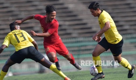 Timnas U-22 Indonesia Imbang Lawan Malaysia. Pemain Timnas U-22 Gian Zola (tengah) berupaya melewati dua pemain Malaysia Ariff Ar Rasyid Ariffin (kanan) dan Dinesh Rajasingam (kiri) dalam pertandingan Grup B Piala AFF U-22 di Stadion Nasional Olimpiade Phnom Penh, Kamboja, Rabu (20/2/2019). 