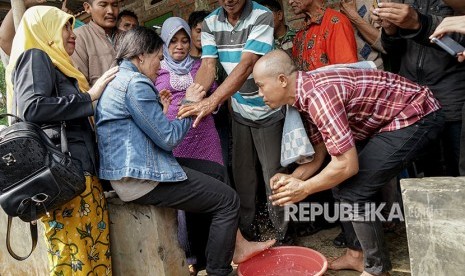 Indonesian migrant worker, Parinah (second left) who had been locked up by her employer for 18 years, returns to her family on Thursday. Her third son, Nurhamdan (right) washes her feet as a sign of respect to the mother at Nusawungu village, Nusawungu, Cilacap, Central Java, Thursday (April 12). 