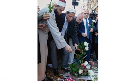 Tokoh Islam Prancis, Imam Hassen Chalghoumi (kedua dari kiri) bersama tokoh agama lainnya meletakkan bunga di dekat Bataclan Theatre. Paris, Ahad (15/11).