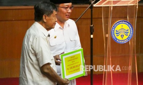 Tokoh sastrawan Jawa Barat Ajip Rosidi (kiri) mendapat bantuan dari Gubernur Jawa Barat untuk perpustakaannya pada acara Milad Ajip Rosidi ke-81, di Kampus Institut Seni dan Budaya Indonesia (ISBI), Kota Bandung, Kamis (31/1). 