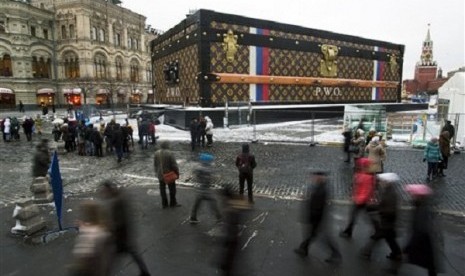 Tourists and visitors pass by a two-story Louis Vuitton suitcase erected at the Red Square in Moscow, Russia, Wednesday, Nov. 27, 2013.