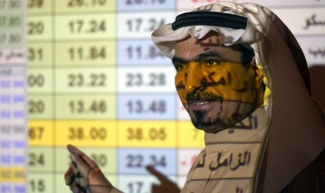 Trader Arab Saudi berbicara di depan papan saham di Arab National Bank di Riyadh, Kamis (12/12). Valuasi perusahaan mencapai 2 triliun dolar AS setelah tiga hari IPO.