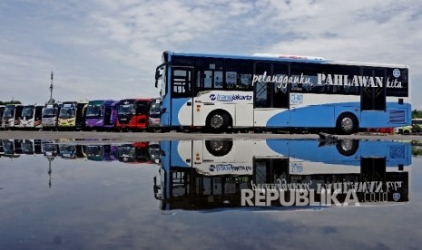  Transjakarta melintas di depan bus AKAP yang terparkir di Terminal Terpadu Pulo Gebang, Jakarta, Selasa (3/1).