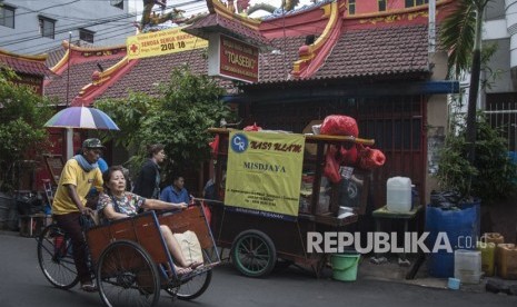 Tukang becak mengangkut penumpang saat melintas di kawasan Petak Sembilan, Glodok, Jakarta, Selasa (16/1).