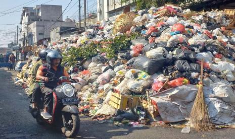 Warga melintas di dekat tumpukan sampah sekitar Pasar Kosambi, Kota Bandung, Jawa Barat, Jumat (6/10/2023).