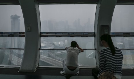 Turis asal Cina melihat pemandangan Singapura yang tertutup kabut asap dari salah satu kabin Singapore Flyer (23/10).