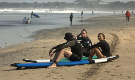 Turis asing duduk di pantai Kuta, Bali, Indonesia Selasa, 22 Maret 2022. Ditjen Imigrasi Bantah KUHP Baru Turunkan Kedatangan Turis Asing