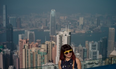 Turis berfoto dengan latar belakangan Kota Hong Kong.