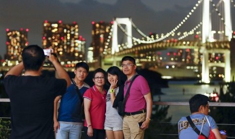 Turis berfoto dengan latar Jembatan Pelangi di Daiba Marine Park, Tokyo, Jepang.