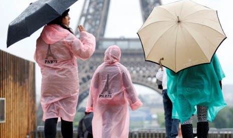 Turis berjalan-jalan di pelataran Trocadero di depan Menara Eiffel saat hujan mengguyur Paris, Prancis, pada 30 Mei 2016. 