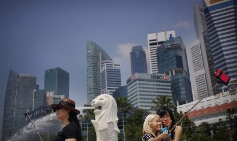 Turis melakukan swafoto dengan latar Patung Merlion, salah satu atraksi wisata populer di Singapura.