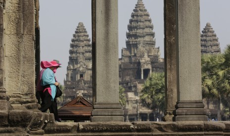 Turis melewati kuil Angkor Wat di Kamboja.