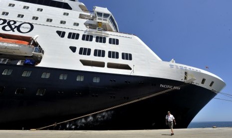 Turis melintas di dekat kapal pesiar Pacific Eden saat berlabuh di Pelabuhan Sukarno-Hatta Makassar, Sulawesi Selatan, Kamis (1/9). 