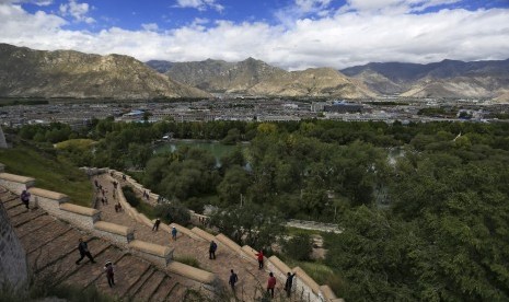 Turis menaiki anak tangga di Istana Potala dengan pemandangan Kota Lhasa, Tibet.