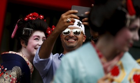 Turis mengenakan kimono melakukan selfie di Kuil Sensoji, Tokyo, Jepang.