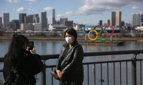  Turis mengenakan masker berfoto dengan latar logo Olimpiade di Odaiba, Tokyo, Jepang, Rabu (29/1). Jepang telah mengevakuasi warganya dari China yang terkunci akibat virus corona.