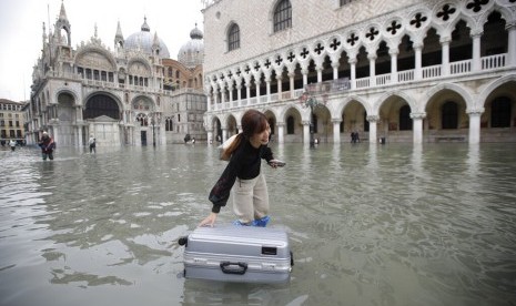 Turis menggeret kopernya di St Mark Square, Venesia, Rabu (13/11). Banjir setinggi 187 cm melanda sebagian besar Venesia.