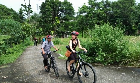 Turis menikmati bersepeda di Desa Bilabante, Lombok.