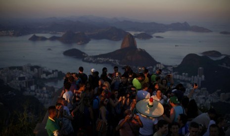 Turis menikmati matahari terbenam di puncak Gunung Corcovado, Rio de Janeiro, Brasil. 